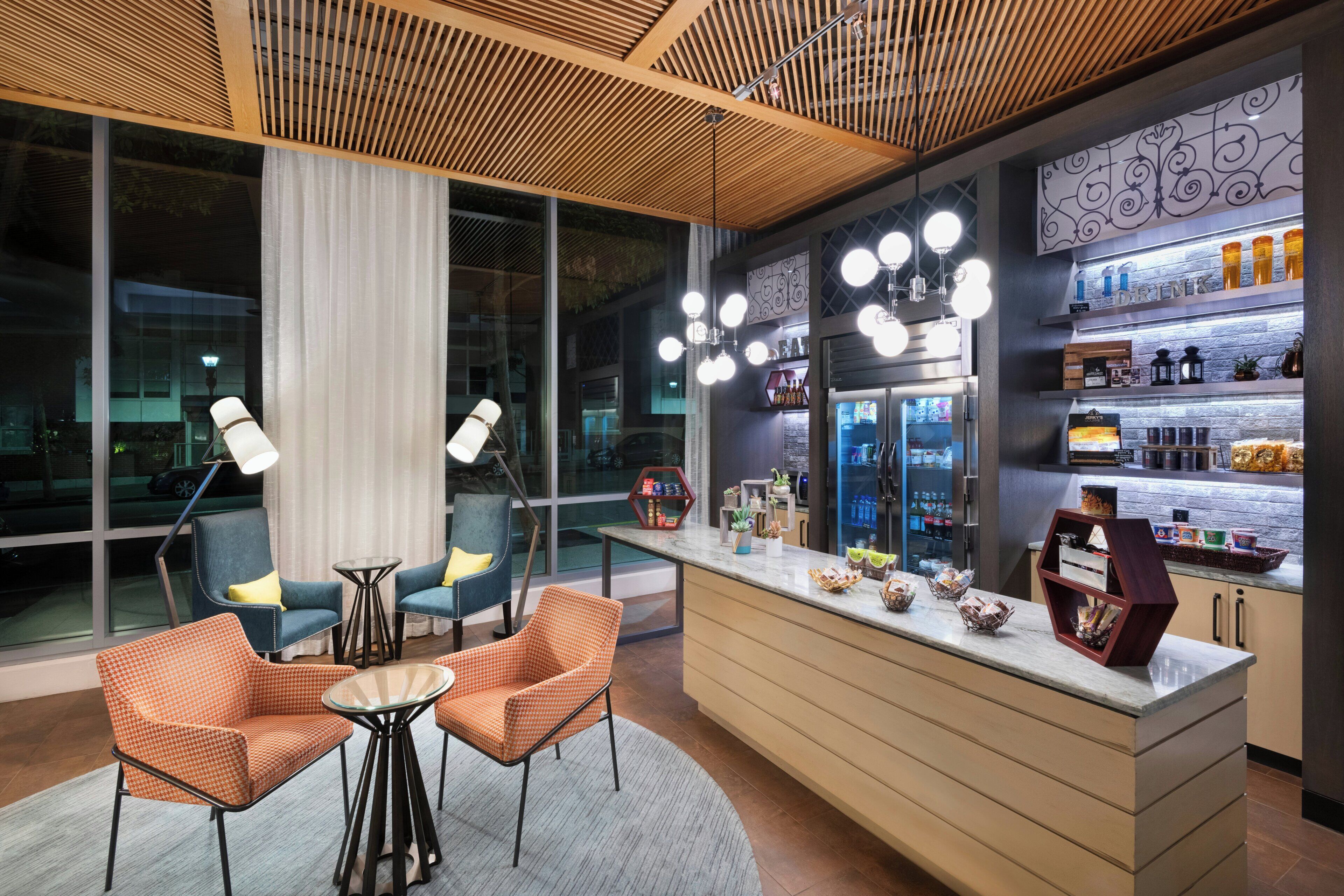 A modern bar area with seating, a refrigerator stocked with beverages, and a decorative wall.