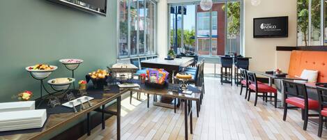 A hotel lobby with a reception desk, seating area, and large windows offering views of the city.