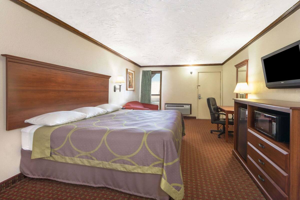 A hotel room with a bed, a desk, a television, and a microwave.