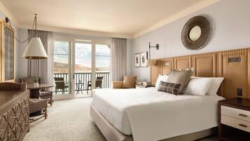 A hotel room with a large bed, a desk, a chair, and a balcony with a view.