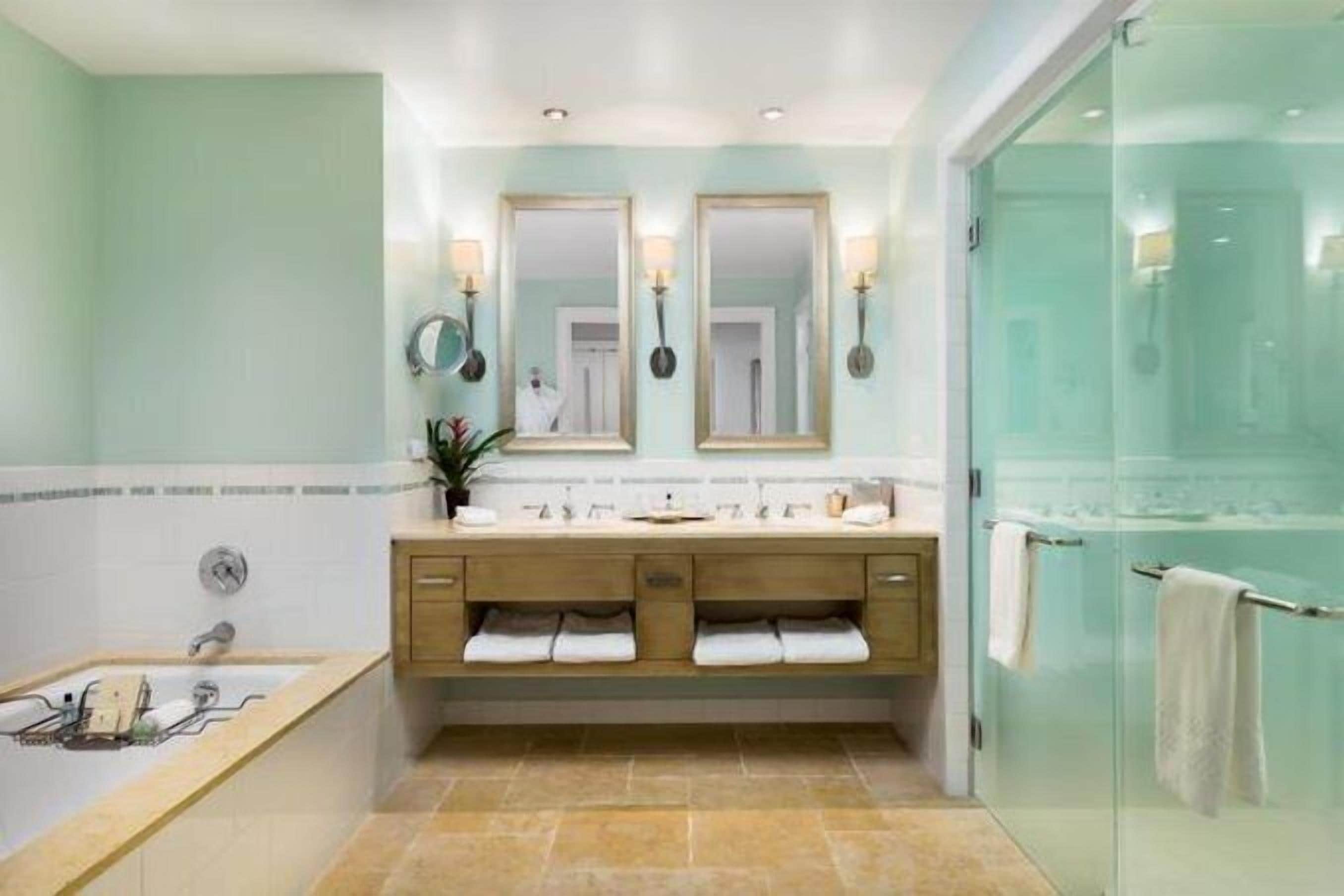 A modern bathroom with a glass-enclosed shower, a freestanding bathtub, and a vanity with two sinks.