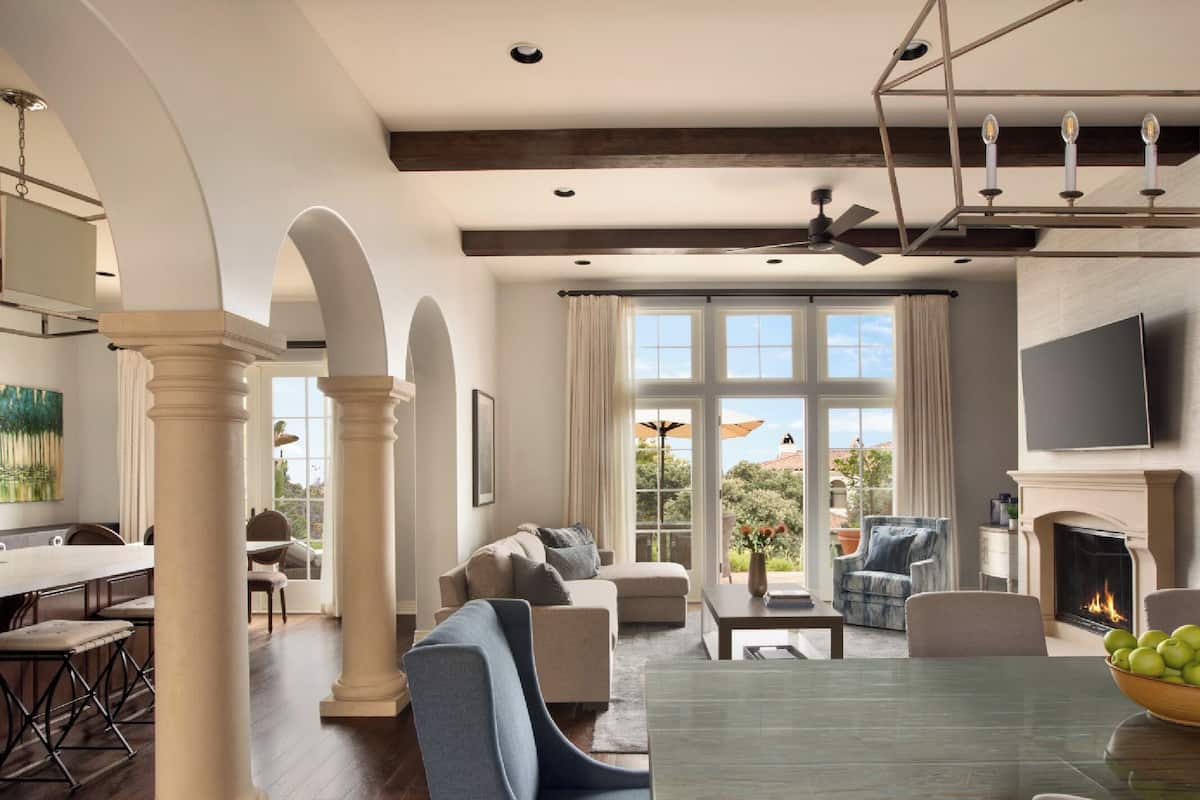 A spacious living room with a dining area, large windows, and a fireplace.