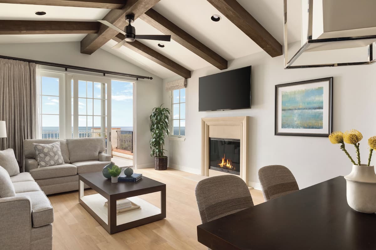 Sala de estar con sofá, mesa de centro, chimenea, televisor y vista al exterior.