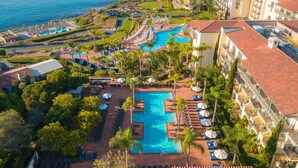 A resort with a central pool, multiple balconies, and a view of the ocean. - Terranea Resort (Rancho Palos Verdes)