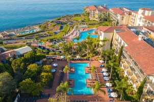 Un resort con piscina central, varios balcones y vista al océano.