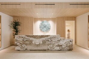 A reception area with a marble counter, a large decorative wall piece, and a potted plant.