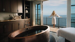 Un baño moderno con una bañera independiente, un ventanal con vistas al mar y un balcón amplio.