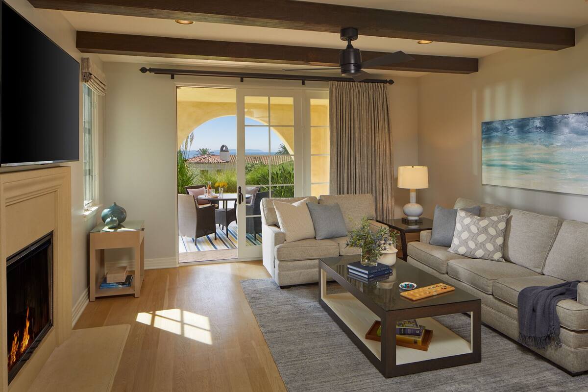 A living room with a fireplace, a sofa, a coffee table, and a view of the outdoors.
