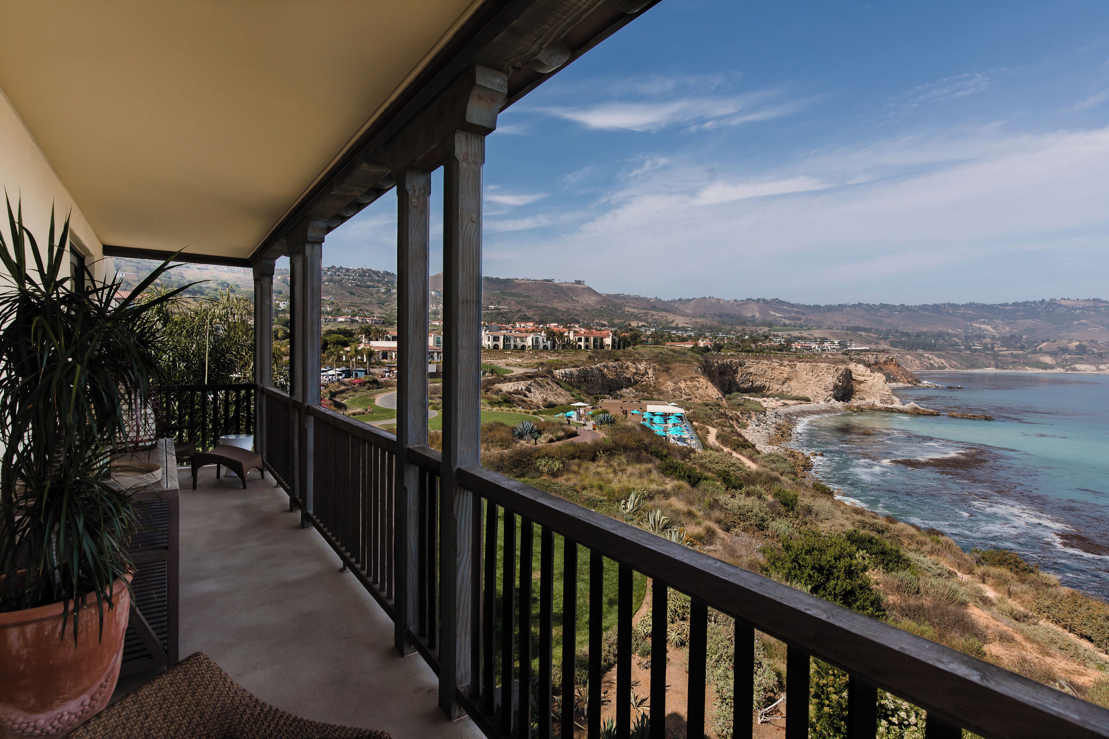 A balcony with a view of the ocean and a distant town.