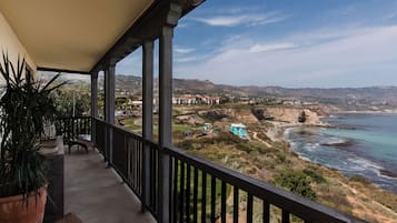 A balcony with a view of the ocean and a distant town.