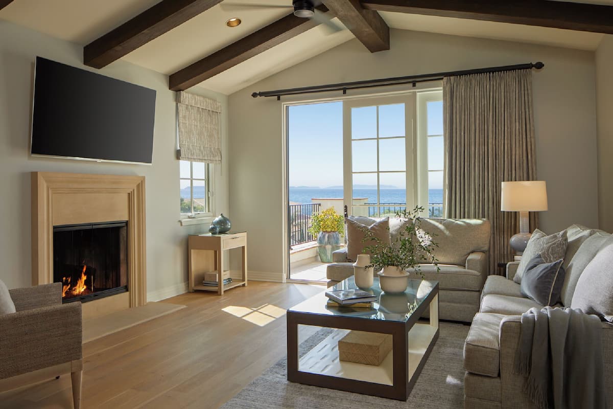 Un salón espacioso con chimenea, un ventanal con vistas al mar y una zona de estar acogedora.