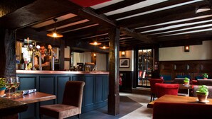 A bar area with a counter, stools, and a seating area with tables and chairs. - The Talbot Inn (Woking)