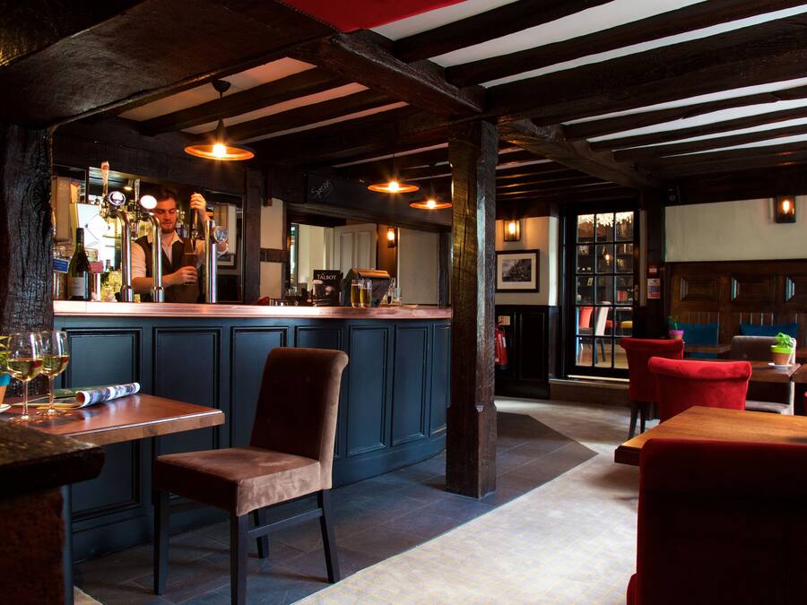 A bar area with a counter, stools, and a seating area with tables and chairs.
