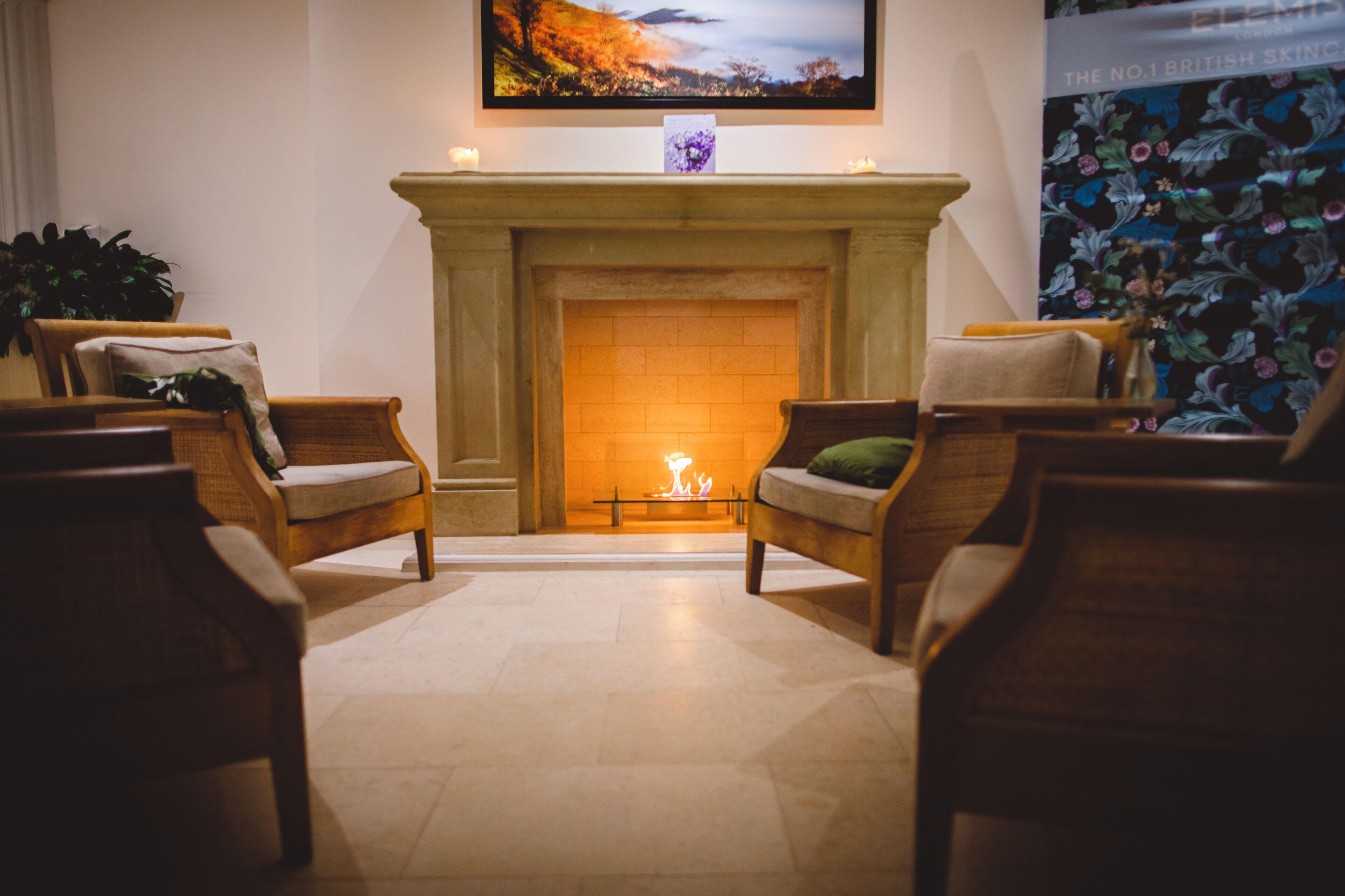 A cozy room with a fireplace, two armchairs, a sofa, and a wall-mounted TV.