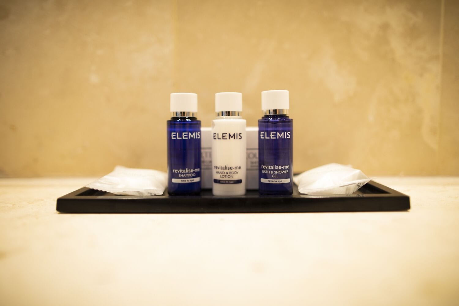 Una bandeja con tres productos Elemis: champú revitalizante, loción revitalizante para manos y cuerpo, y gel de ducha y baño revitalizante.