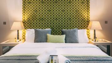 A neatly made bed with pillows, a bedside lamp, and a rolled towel on the bed.