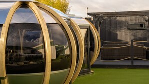 Une structure sphérique en verre, dotée d’une ossature en bois, d’un espace salon en osier et d’une barrière en corde.