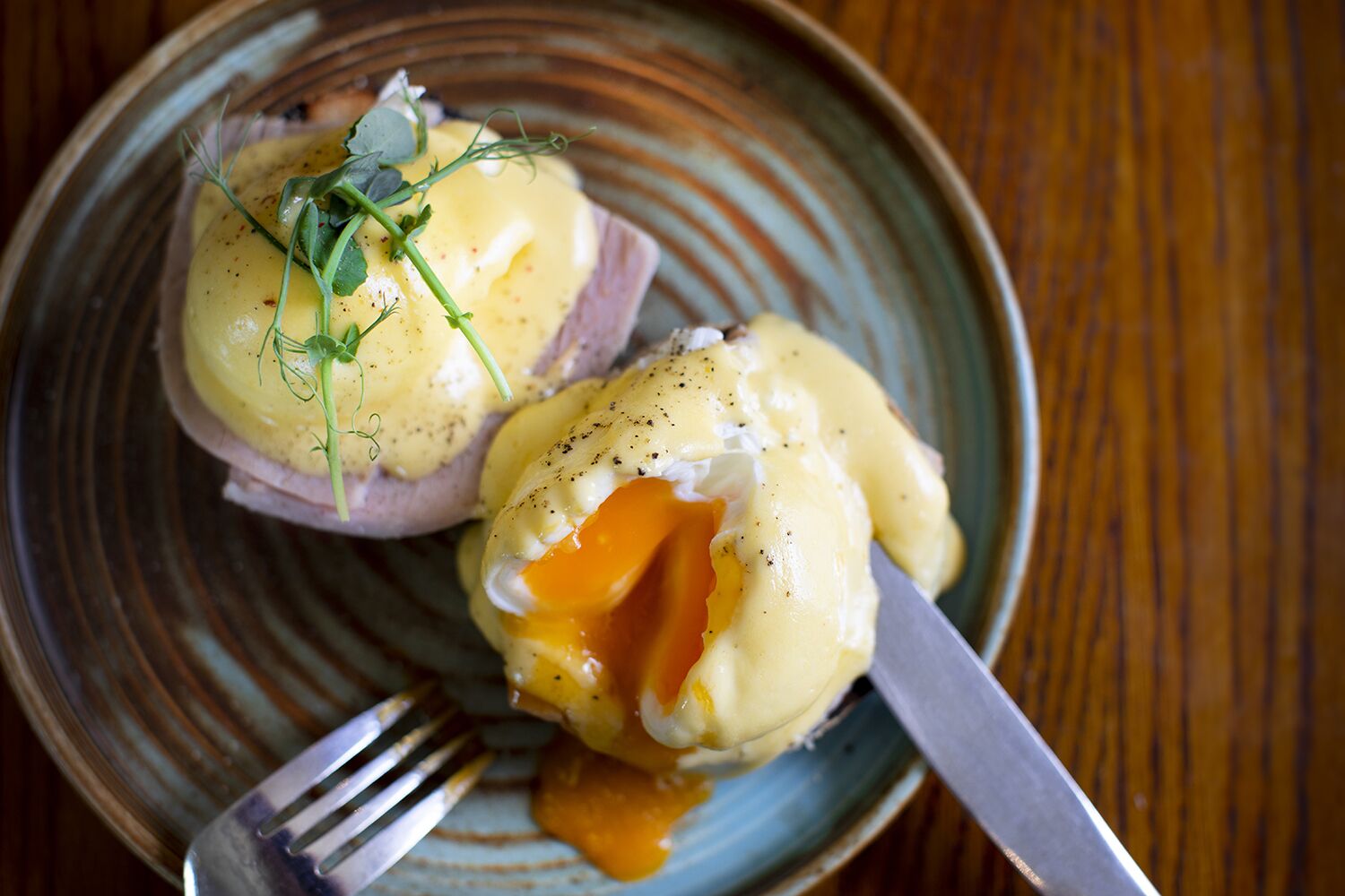 A plate with two poached eggs topped with hollandaise sauce and garnished with herbs.
