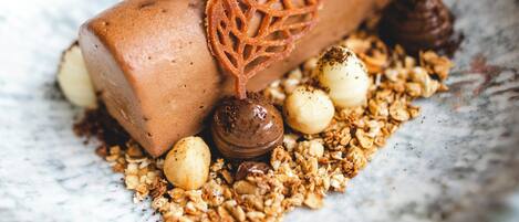Un postre con una hoja caramelizada sobre un plato de granola y bolas de chocolate.