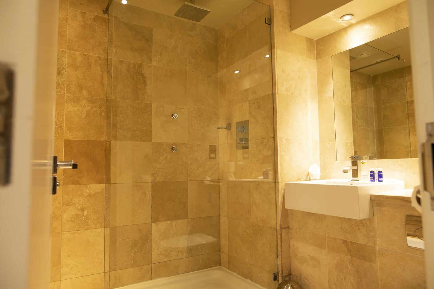 A modern bathroom with a glass-enclosed shower, a white sink, and a large mirror.