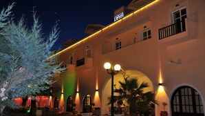 A hotel with a warm exterior, arched windows, and a balcony. - Portiani Hotel (Milos)