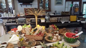 A buffet table with various fruits, vegetables, and condiments. - Portiani Hotel (Milos)