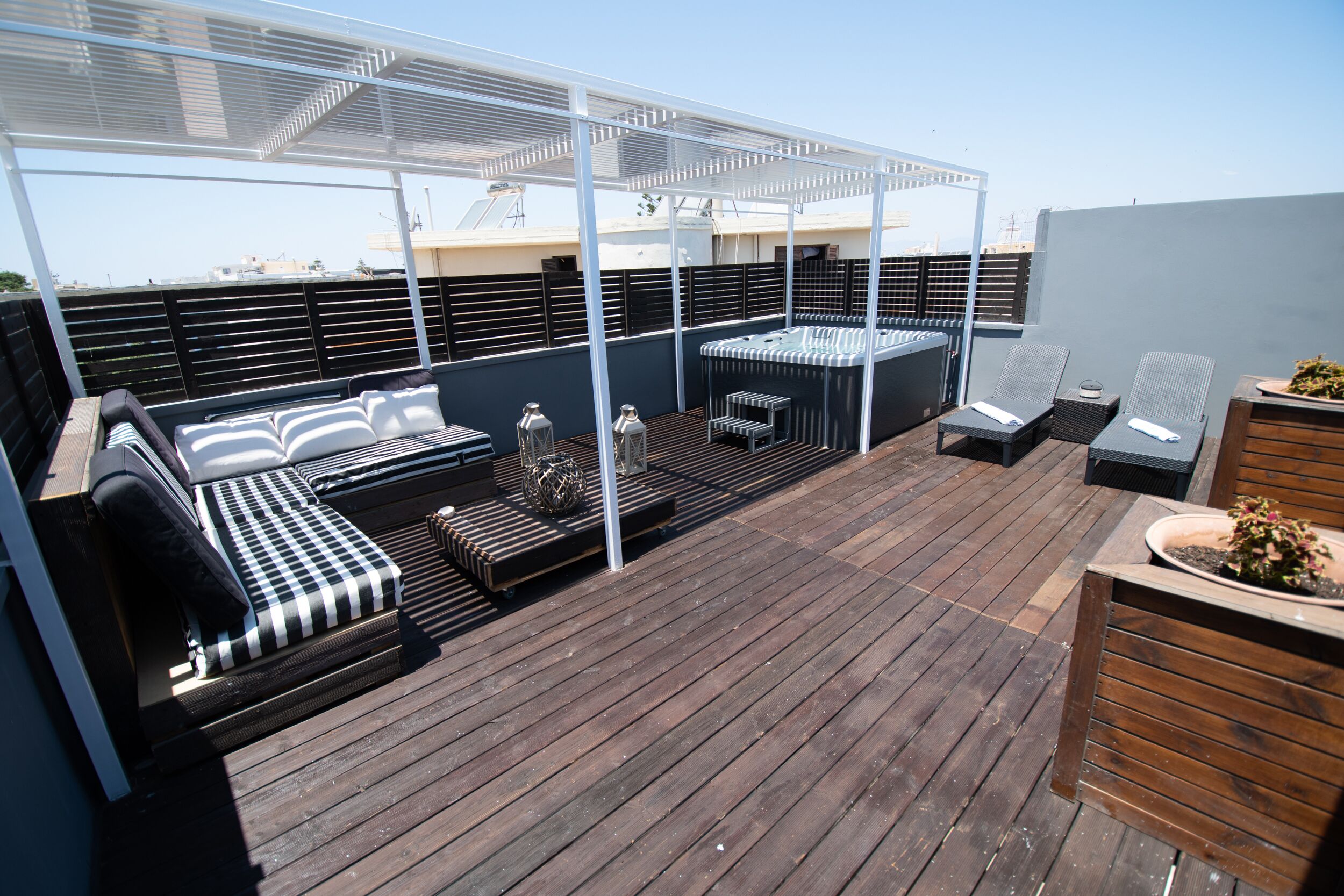Une terrasse sur le toit avec un espace salon, un jacuzzi et une pergola.