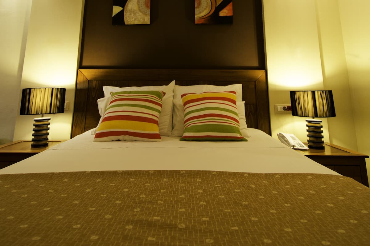 Una habitación de hotel con una cama grande, dos cuadros colgados en la pared y lámparas de noche.