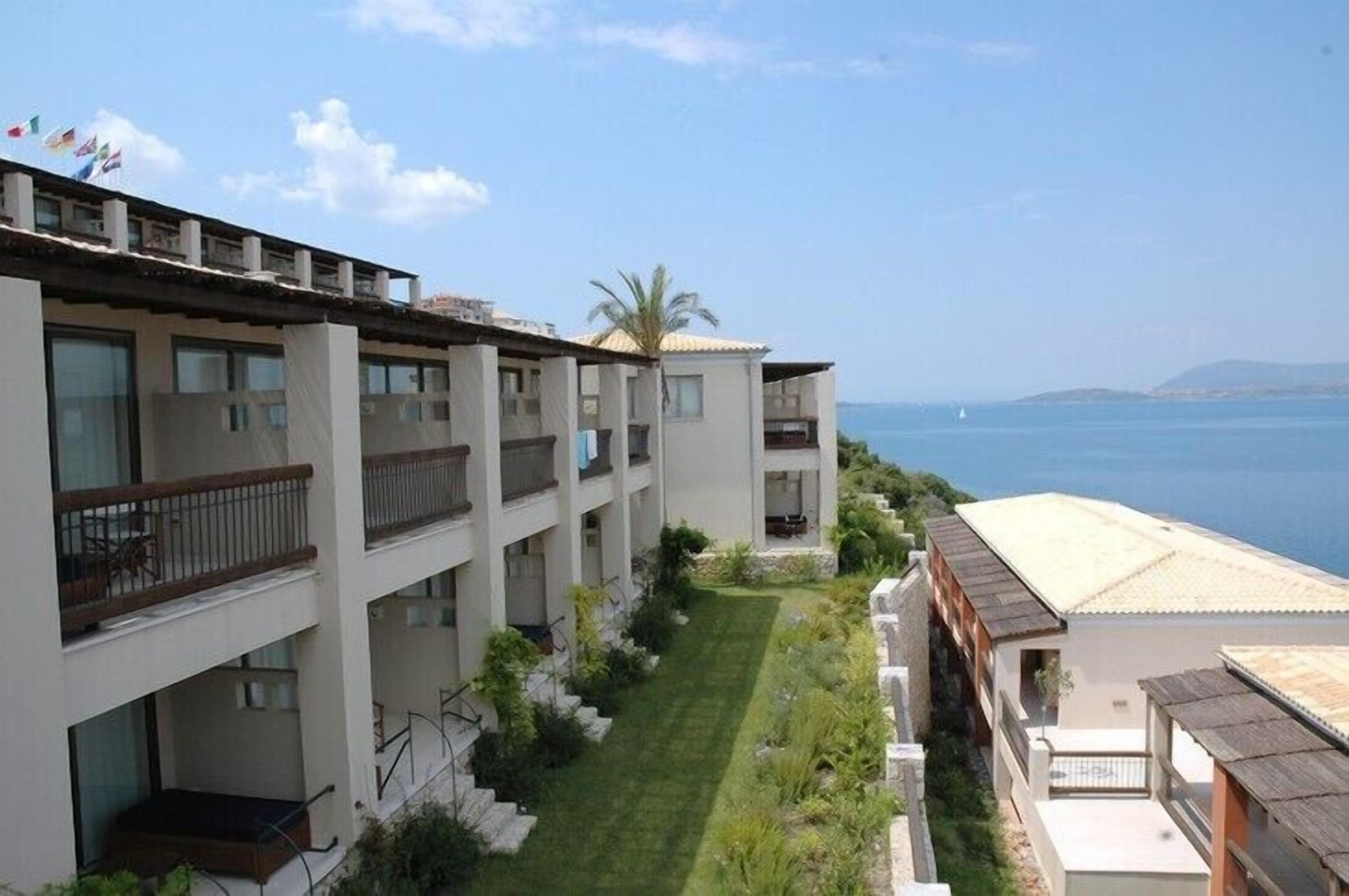 A multi-story hotel with balconies and a view of the sea.