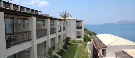 A multi-story hotel with balconies and a view of the sea.