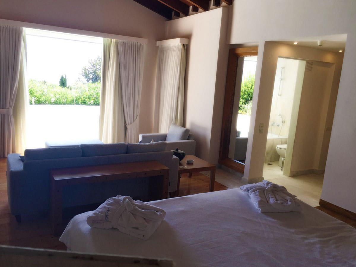 Habitación de hotel con cama, sofá, una mesita y vistas al exterior.