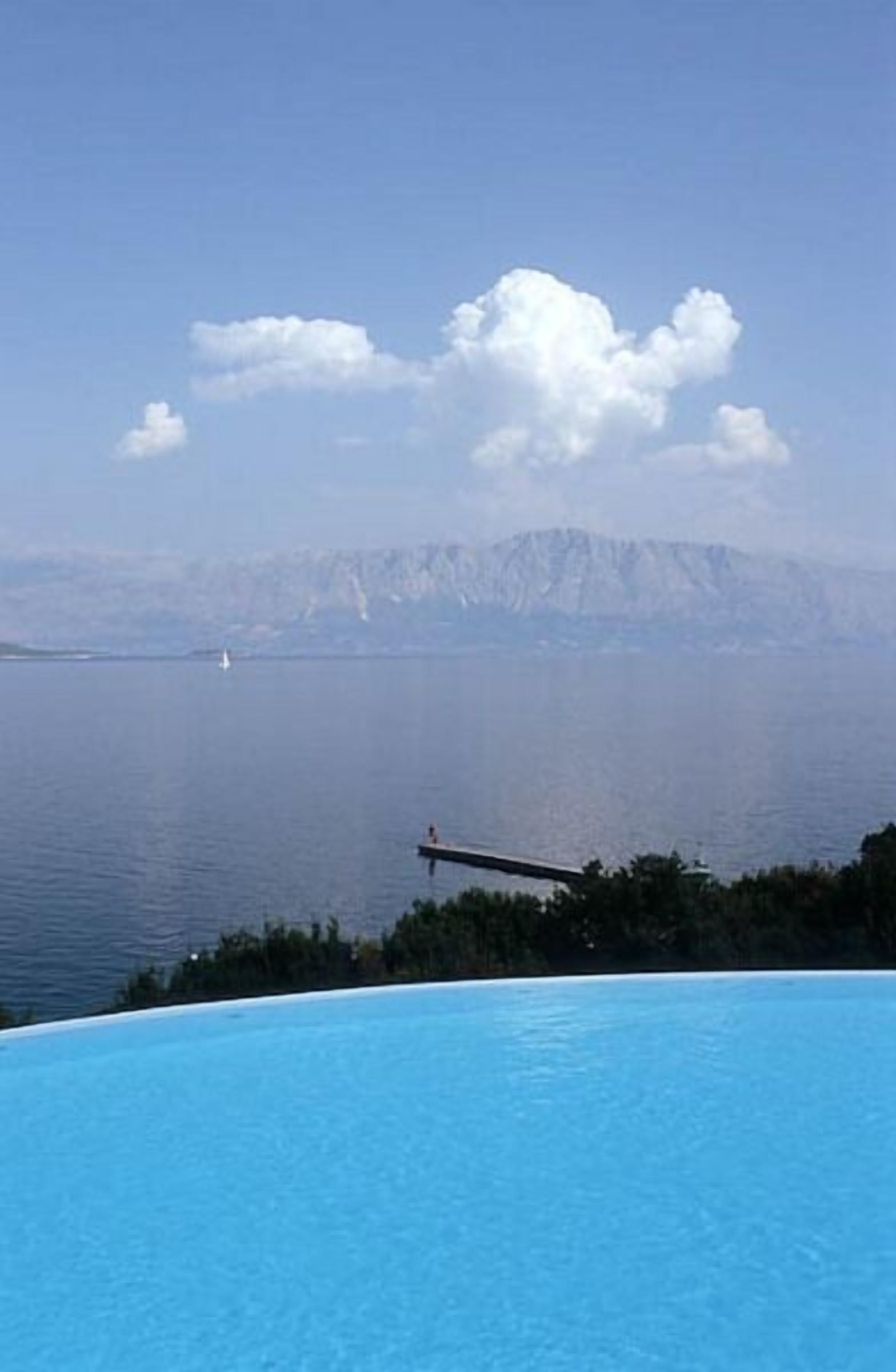 A clear blue pool with a view of a distant island and mountains.