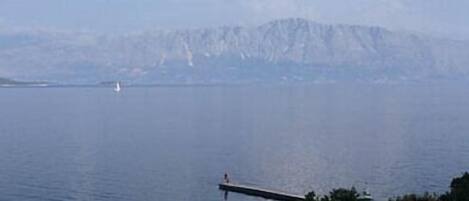 A clear blue pool with a view of a distant island and mountains.