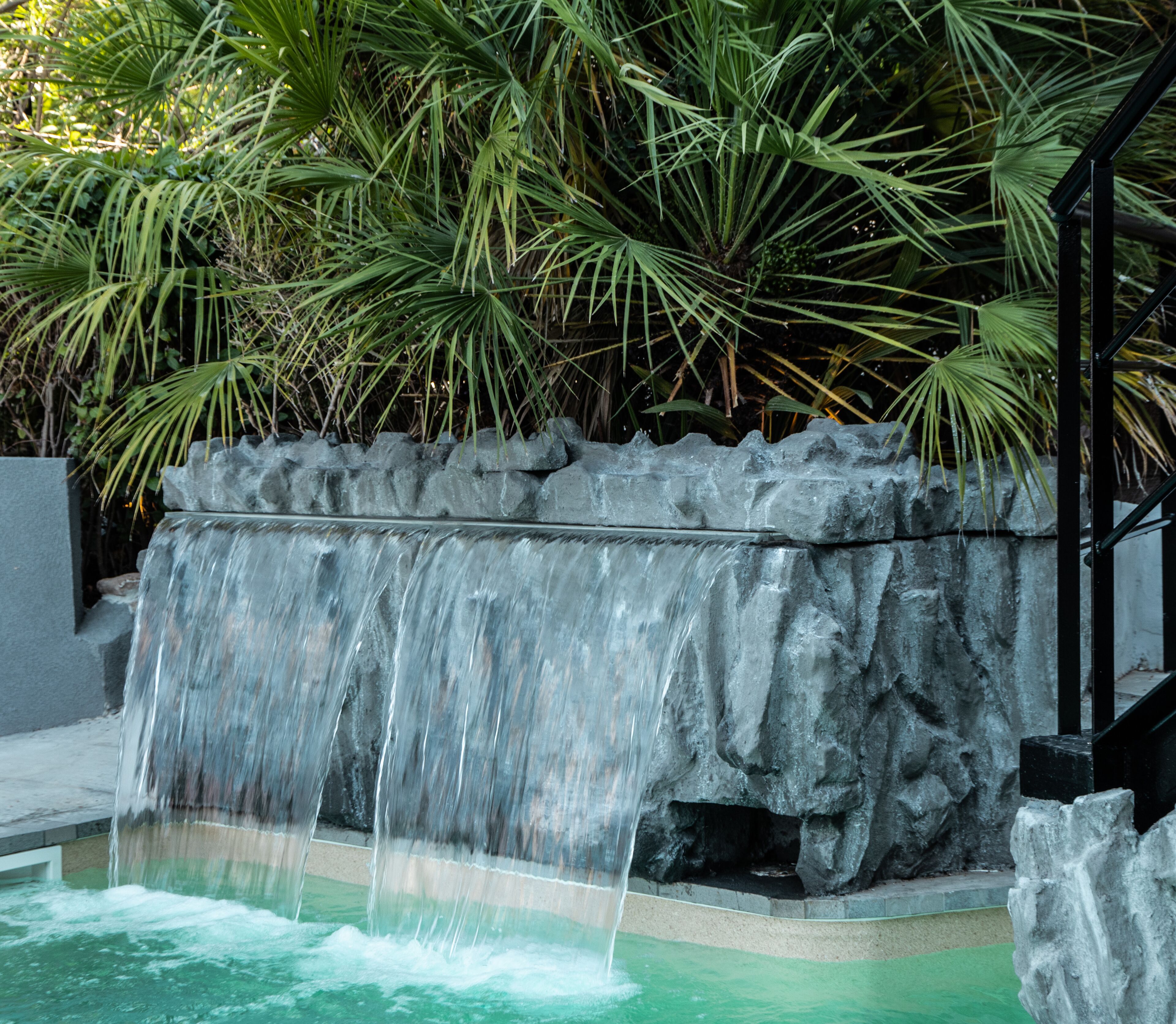 A waterfall feature with a rocky ledge and a pool at the base.