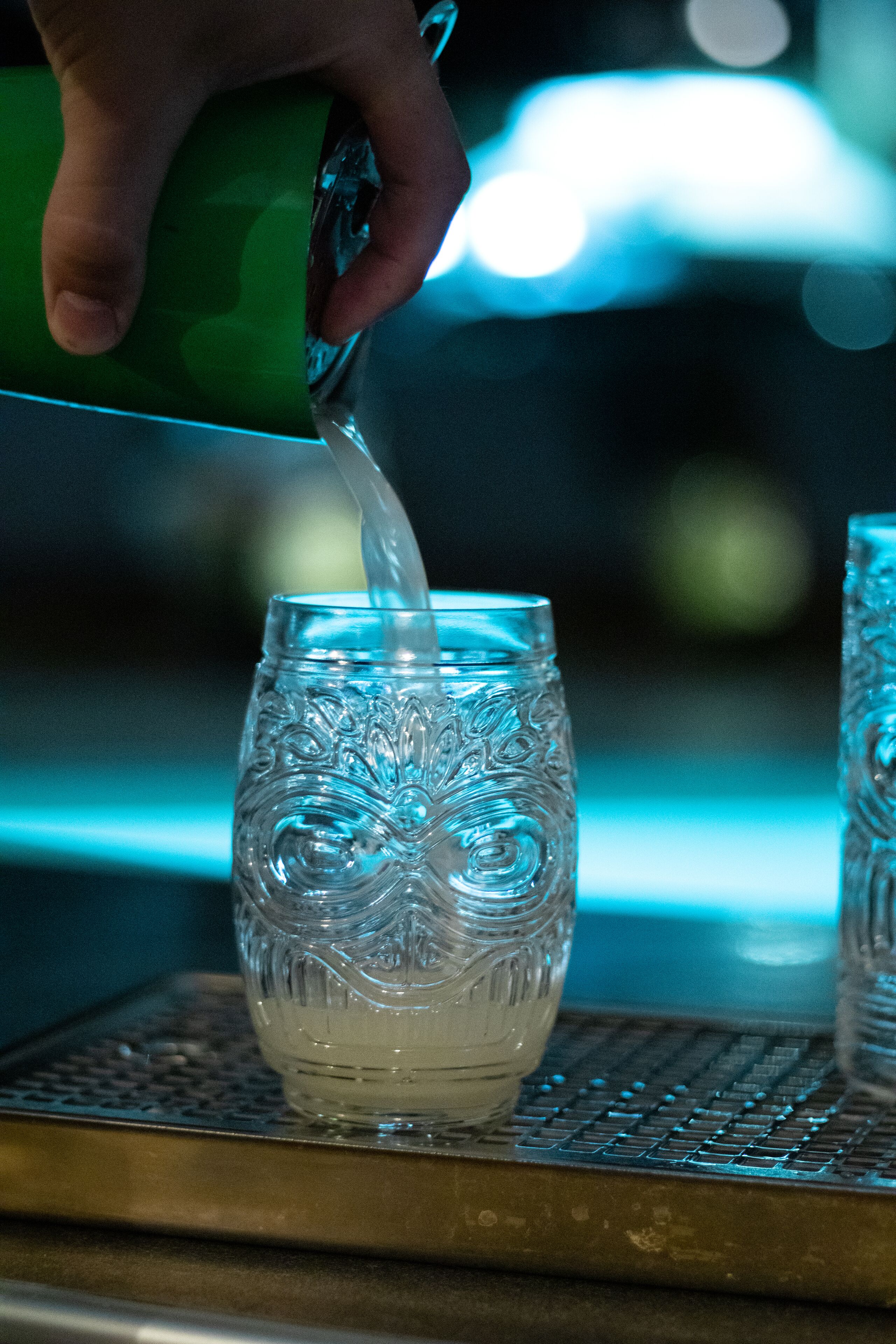A hand pouring liquid into a glass with an intricate design.