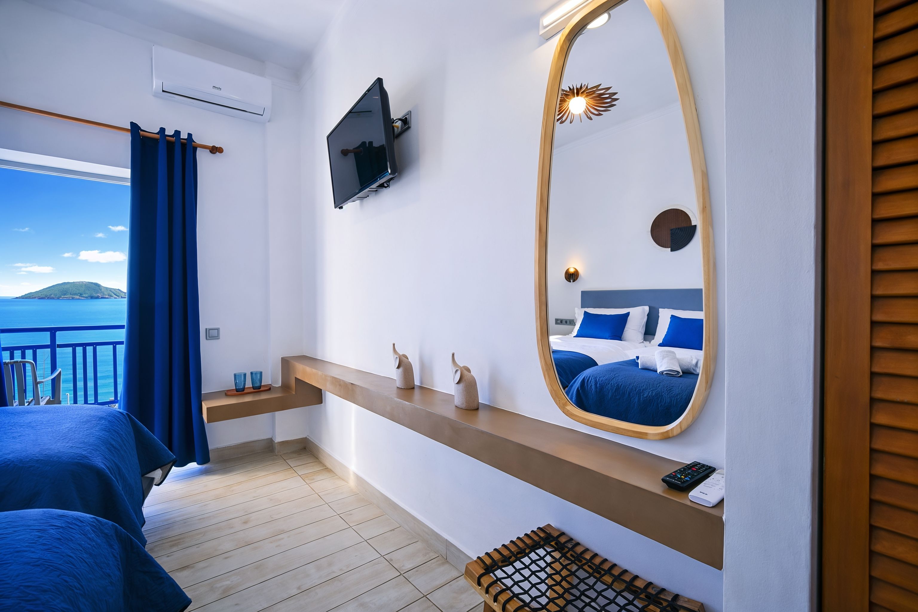 Ein Hotelzimmer mit Bett, Fernseher, Spiegel und Meerblick.