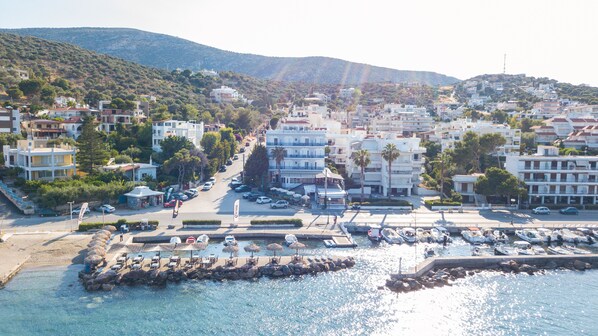 A coastal town with a marina, buildings with balconies, and a hilly backdrop. - Kiani Akti Hotel (Markopoulo Mesogaias)