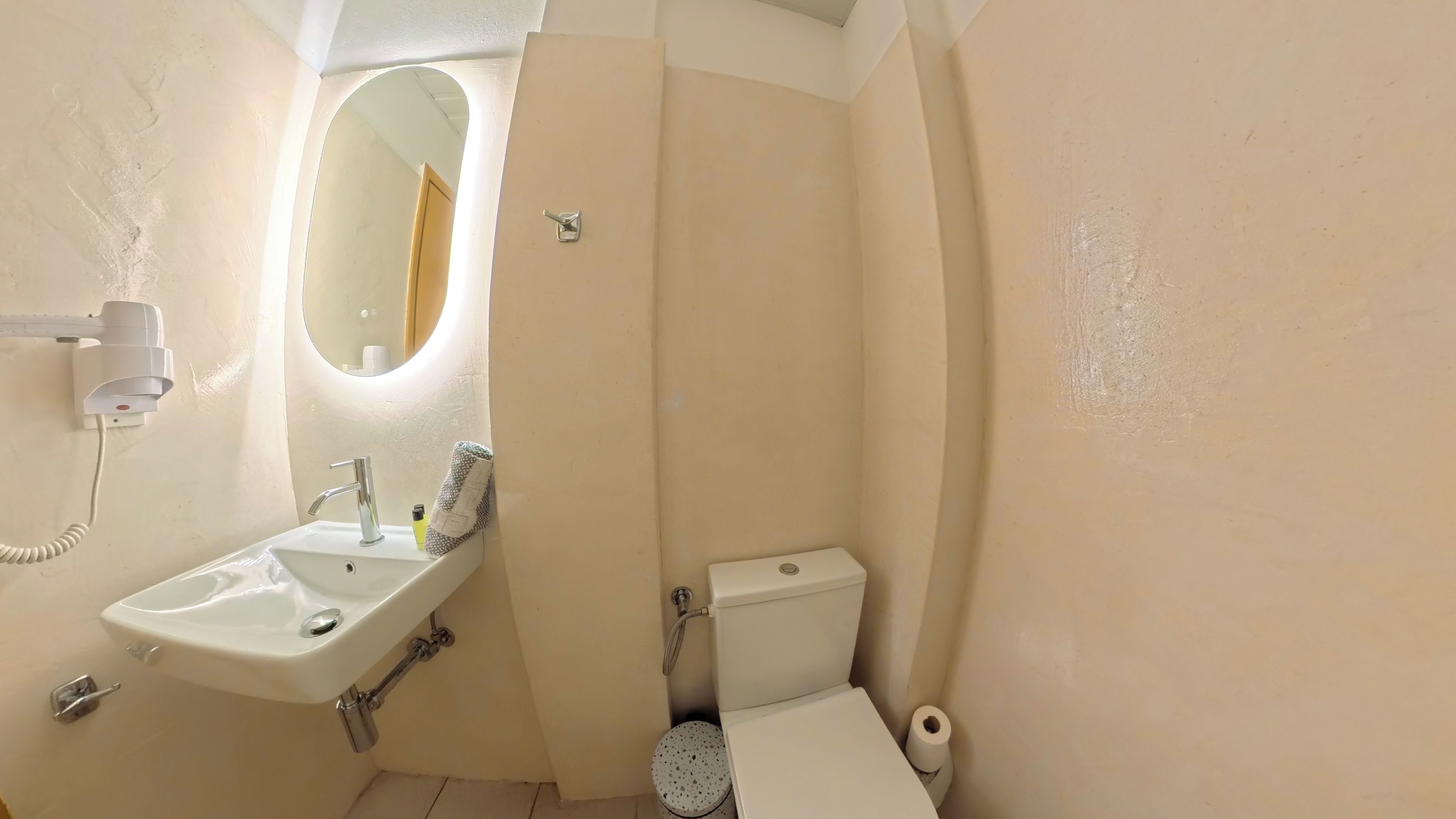 Un baño pequeño con un lavamanos blanco, un espejo, un inodoro y una toalla colgada en la pared.