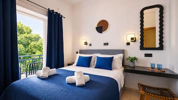Une chambre d’hôtel avec un lit, une table de chevet, un miroir et une vue sur la verdure.