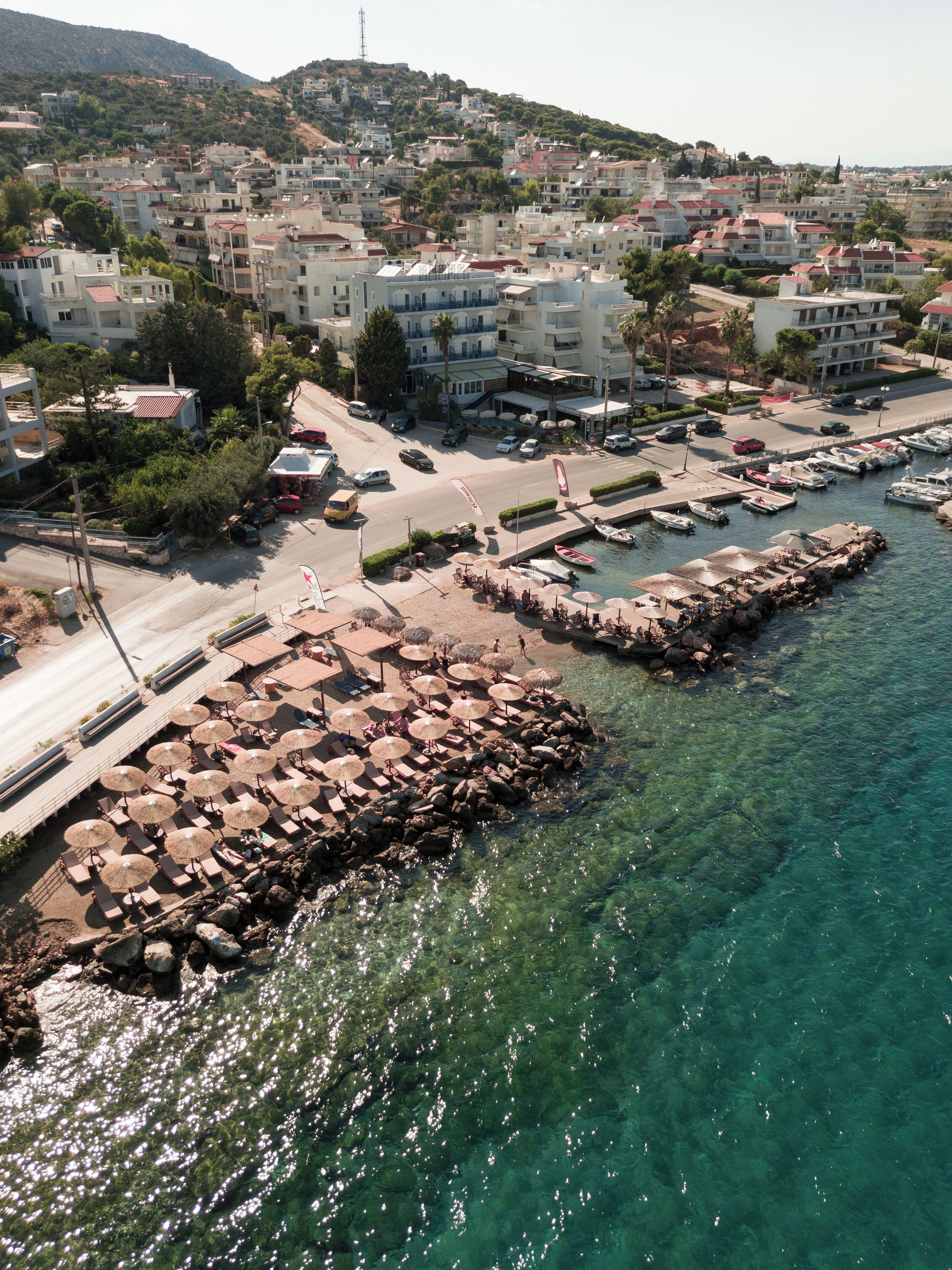 Un pueblo costero con aguas transparentes, un puerto deportivo y edificios con balcones.