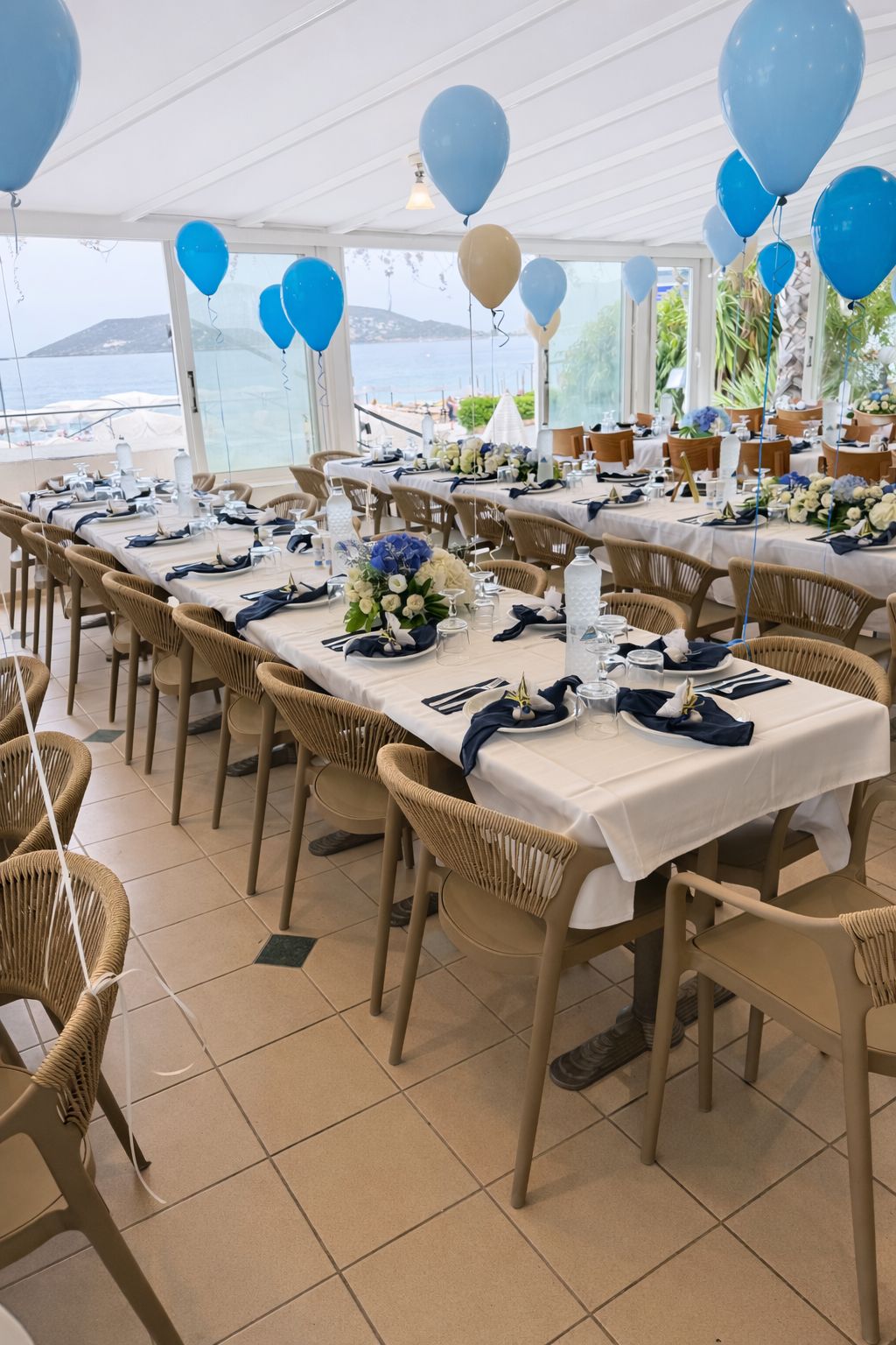 Una sala da banchetto con tavoli apparecchiati per un evento formale, con vista sul mare.