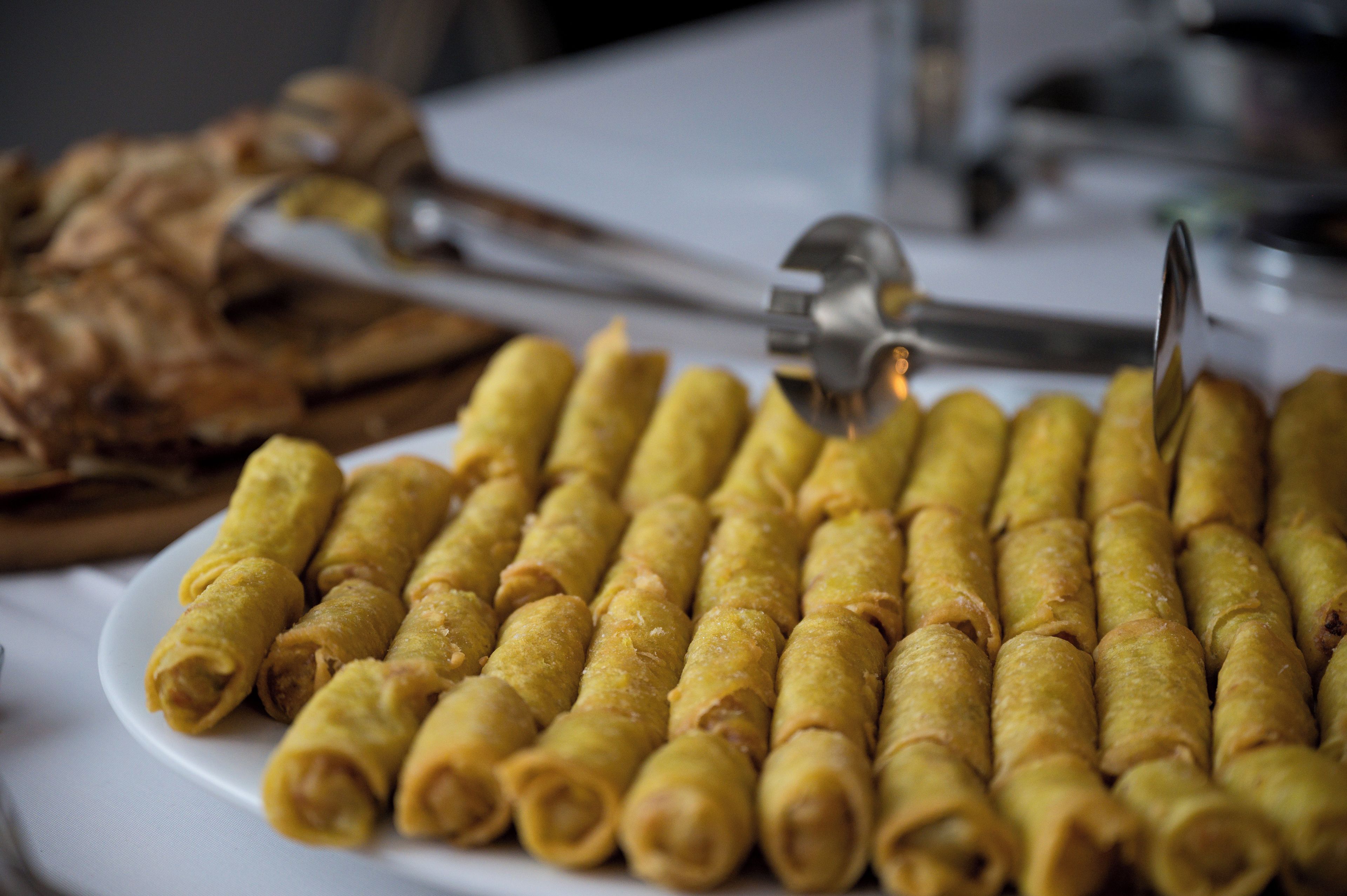 Une assiette remplie de petites bouchées roulées, avec une pince posée dessus.
