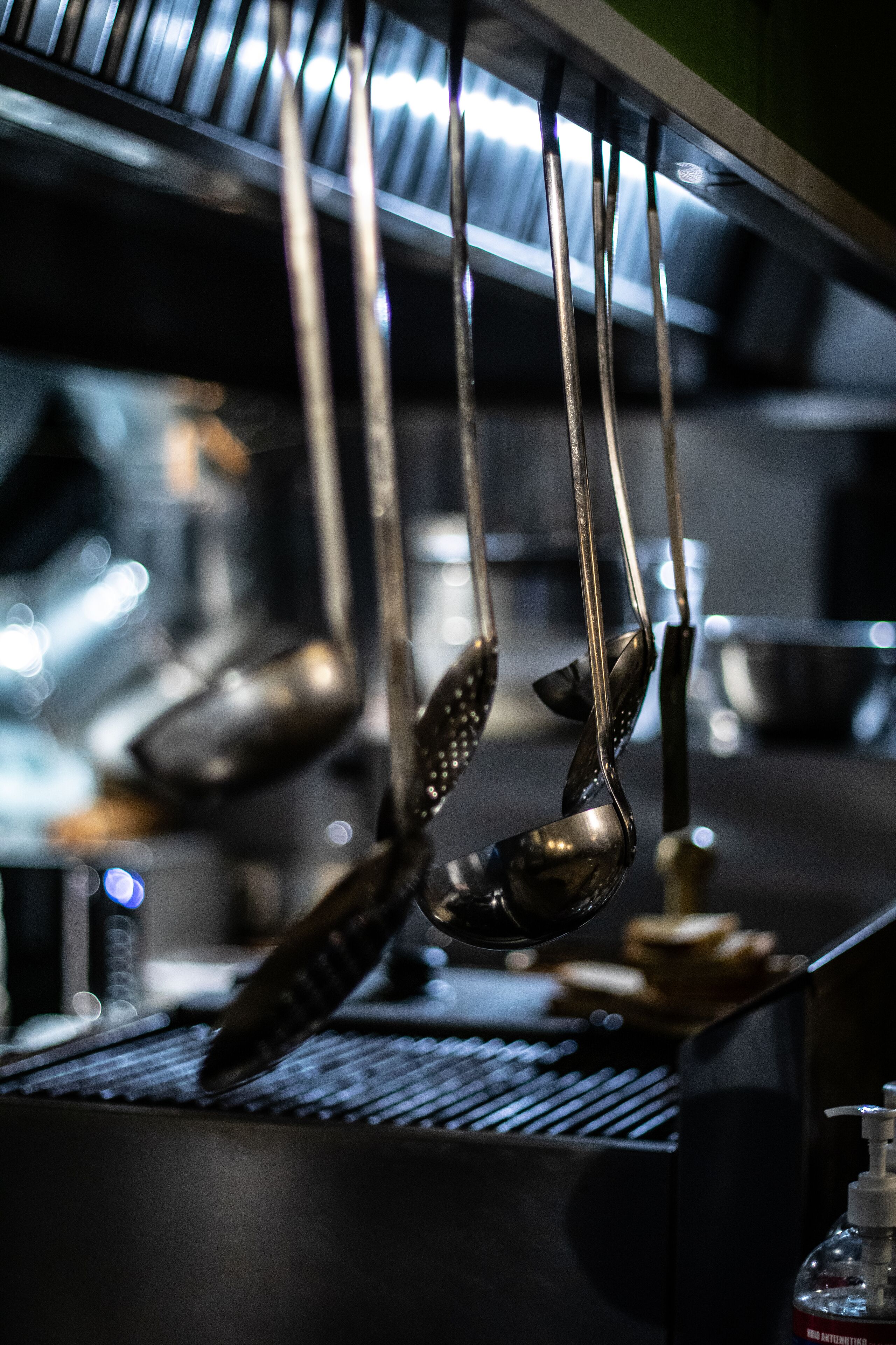 Une cuisine avec des ustensiles suspendus et une bouteille de gel hydroalcoolique.