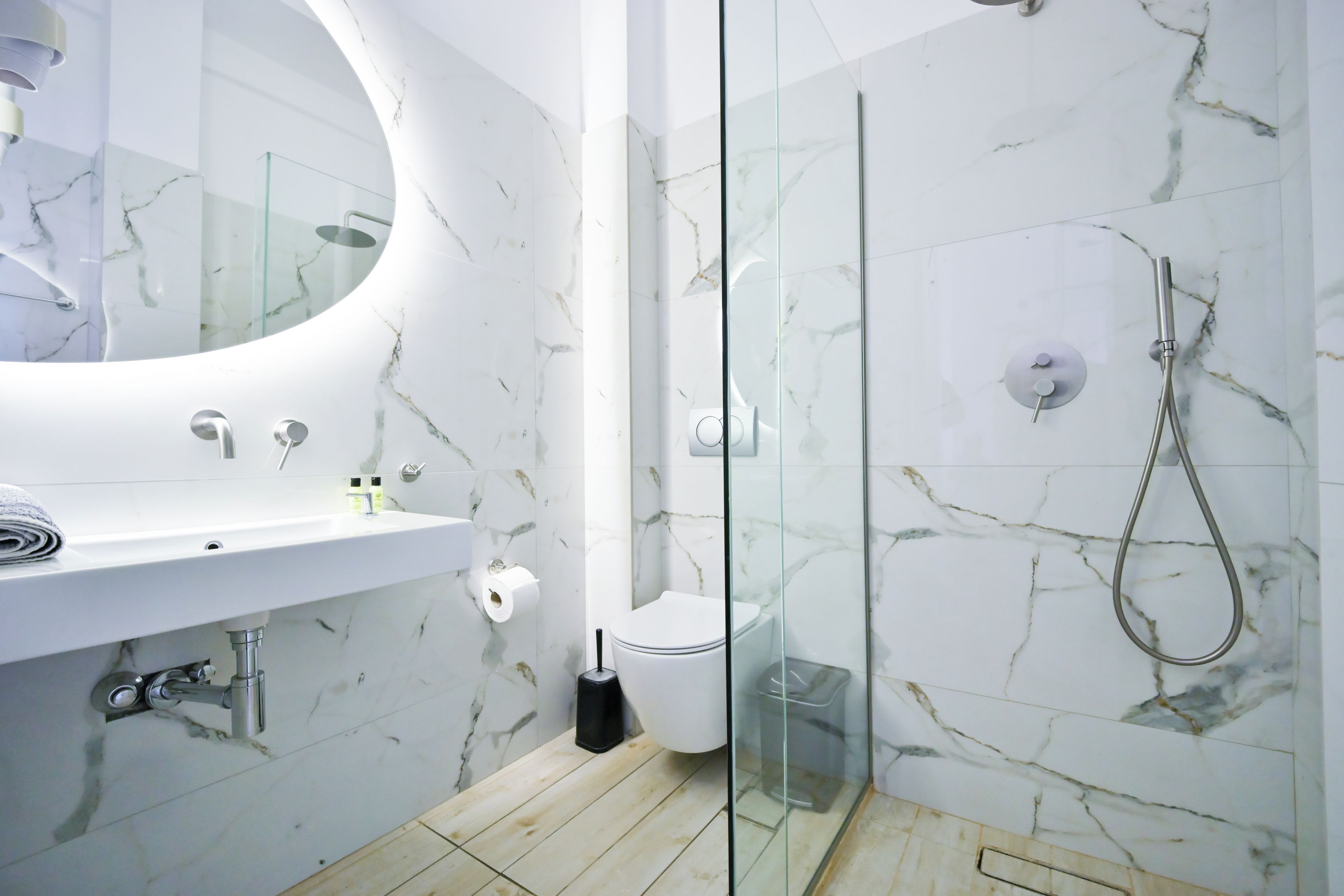 A modern bathroom with a marble vanity, a glass shower enclosure, and a toilet.