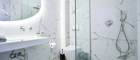 Un baño moderno con tocador de mármol, cabina de ducha de vidrio y un inodoro.