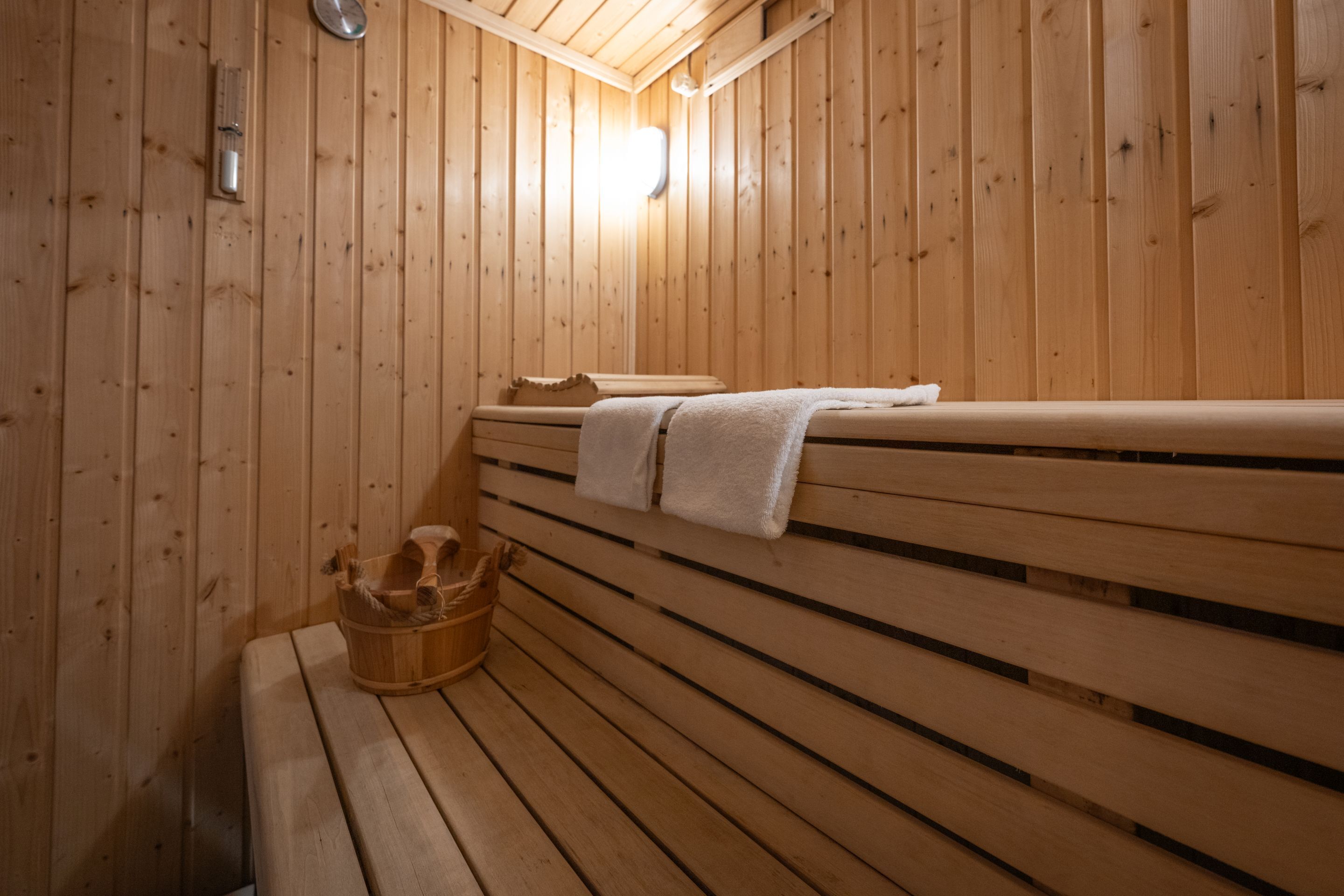 A wooden sauna with benches and a bucket.