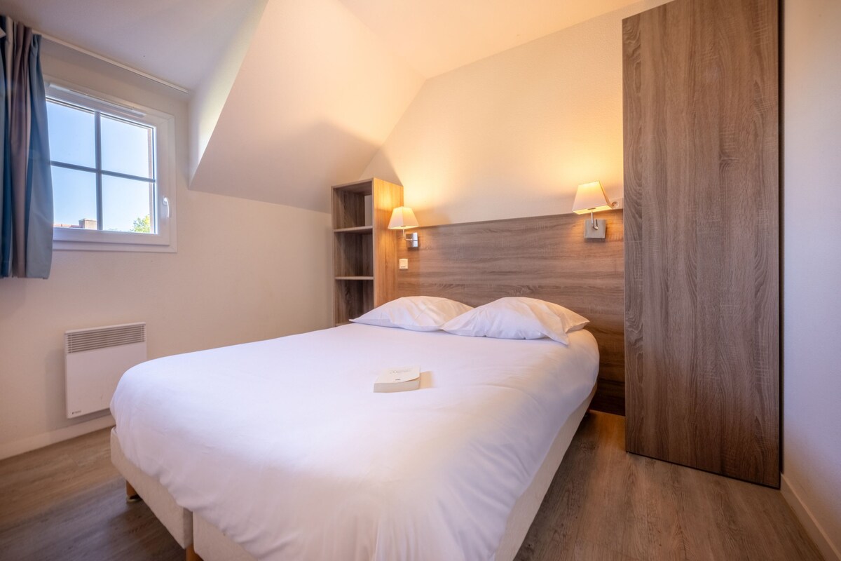 A modern bedroom with a large bed, wooden headboard, and built-in shelving.