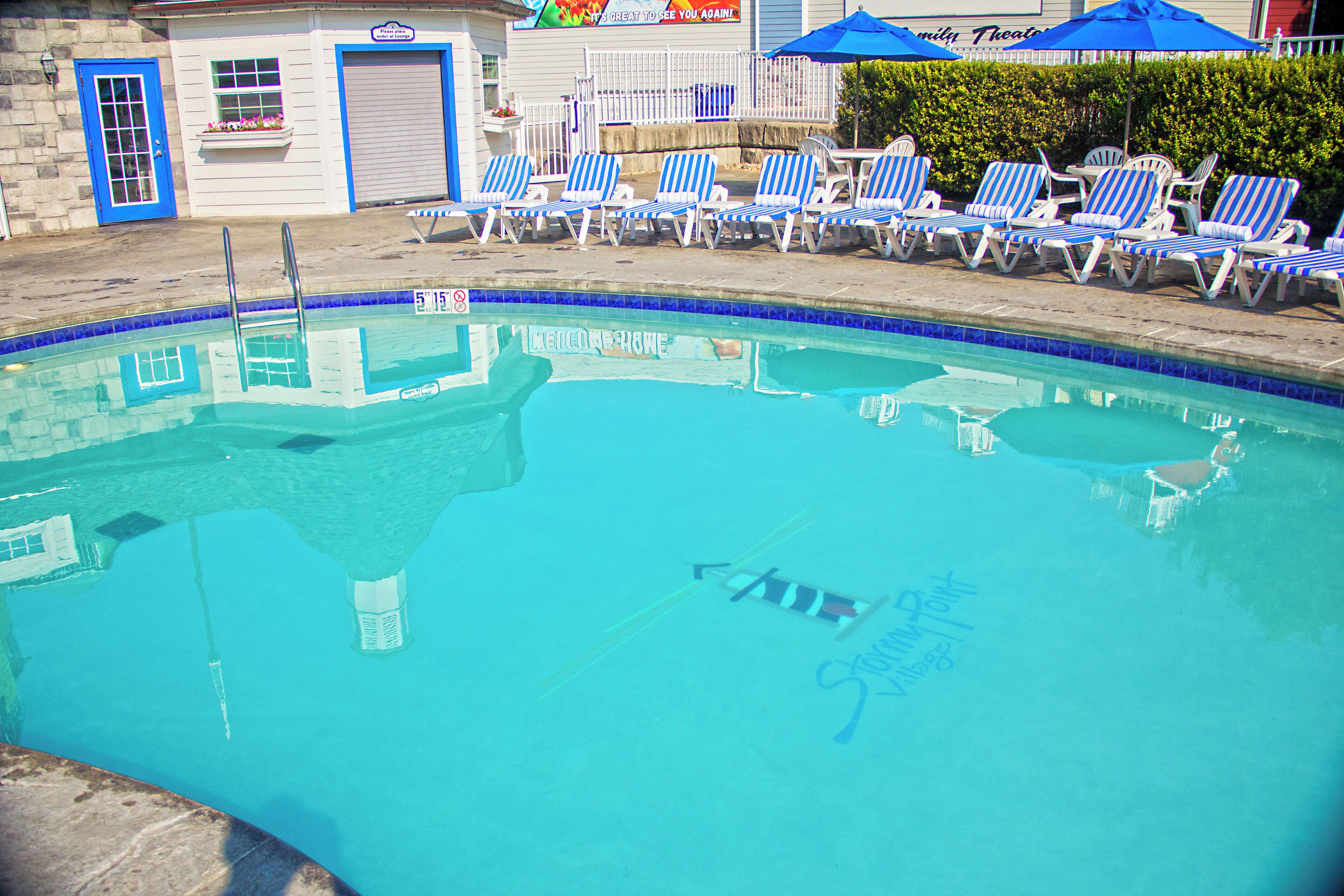 A swimming pool with blue and white lounge chairs arranged around it.