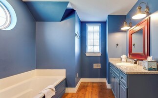 A bathroom with a bathtub, a window, and a vanity with a mirror.