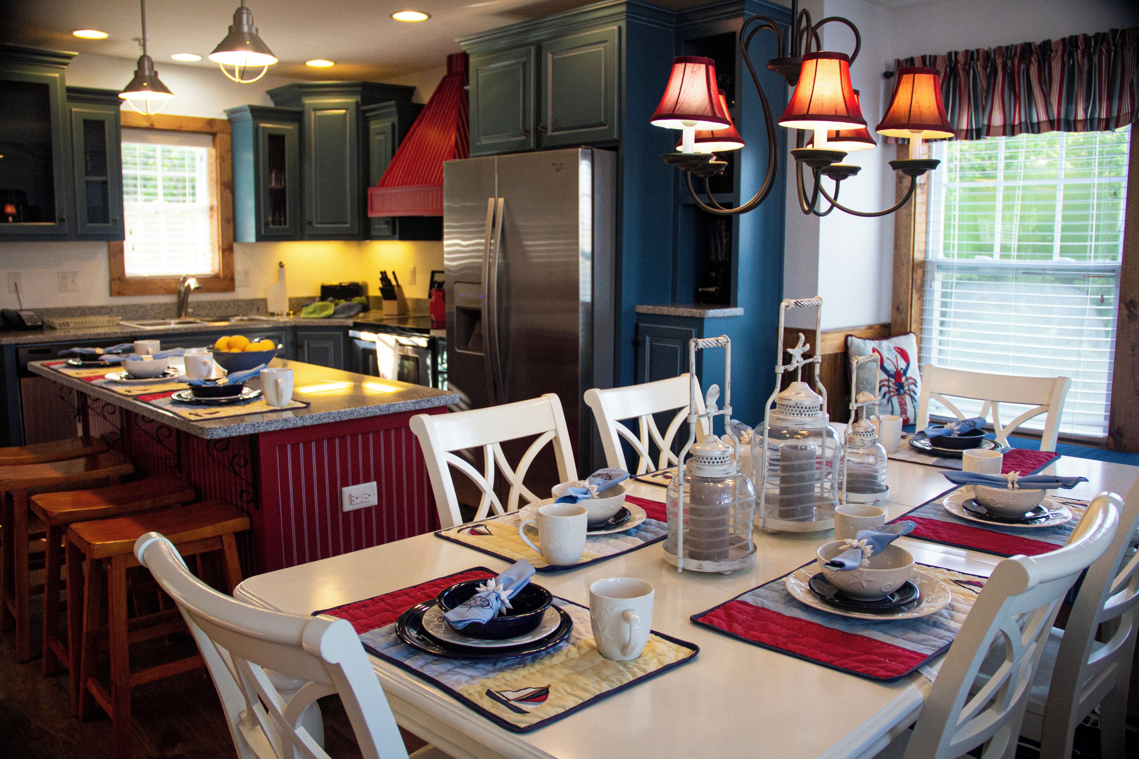 A kitchen with a central island, white chairs, and a dining table set for four.